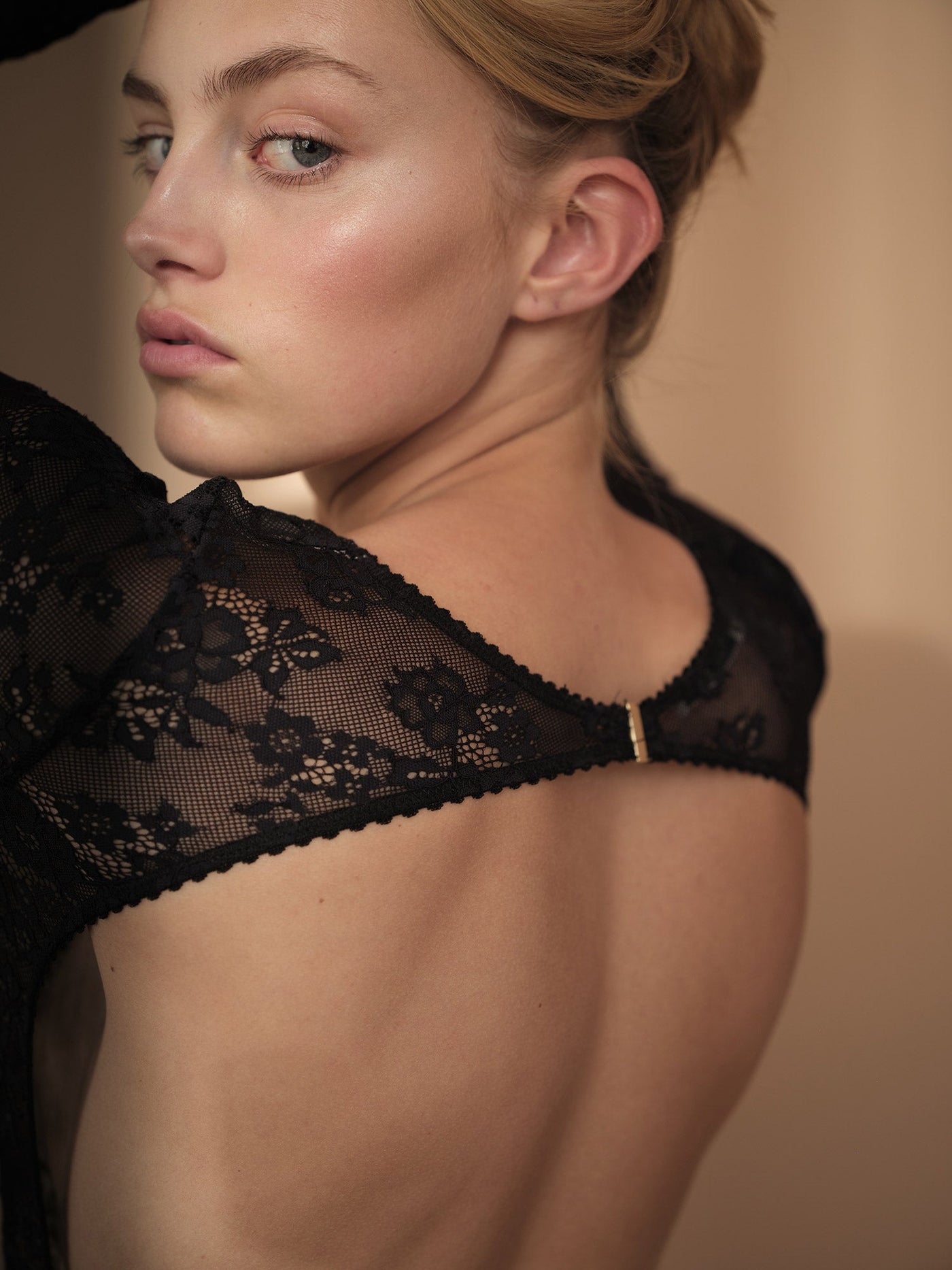 Kvindelig model iført vores Harper Bodystocking Black. Set bagfra i et close up.
