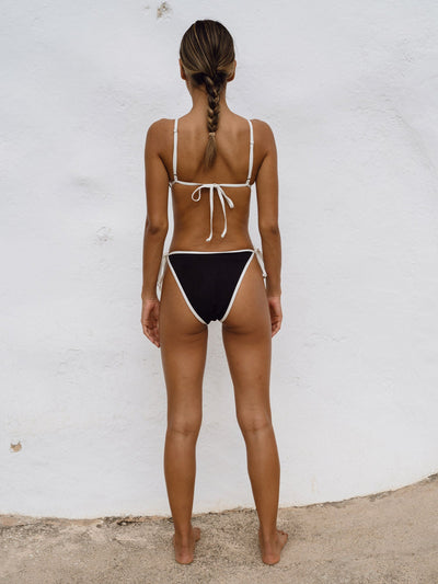 Underprotection tanga bottom  i sort med hvis kant lavet af 85% polyester (genanvendt) og 15% elastan